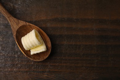 Photo of Tasty butter curl and spoon on wooden table, top view. Space for text