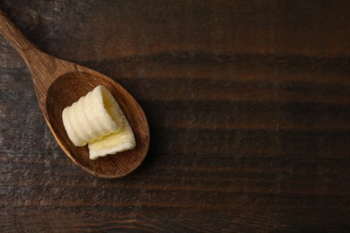 Tasty butter curl and spoon on wooden table, top view. Space for text