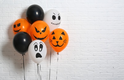 Photo of Color balloons for Halloween party against white brick wall. Space for text
