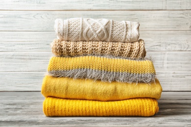 Photo of Stack of warm knitted clothes on table