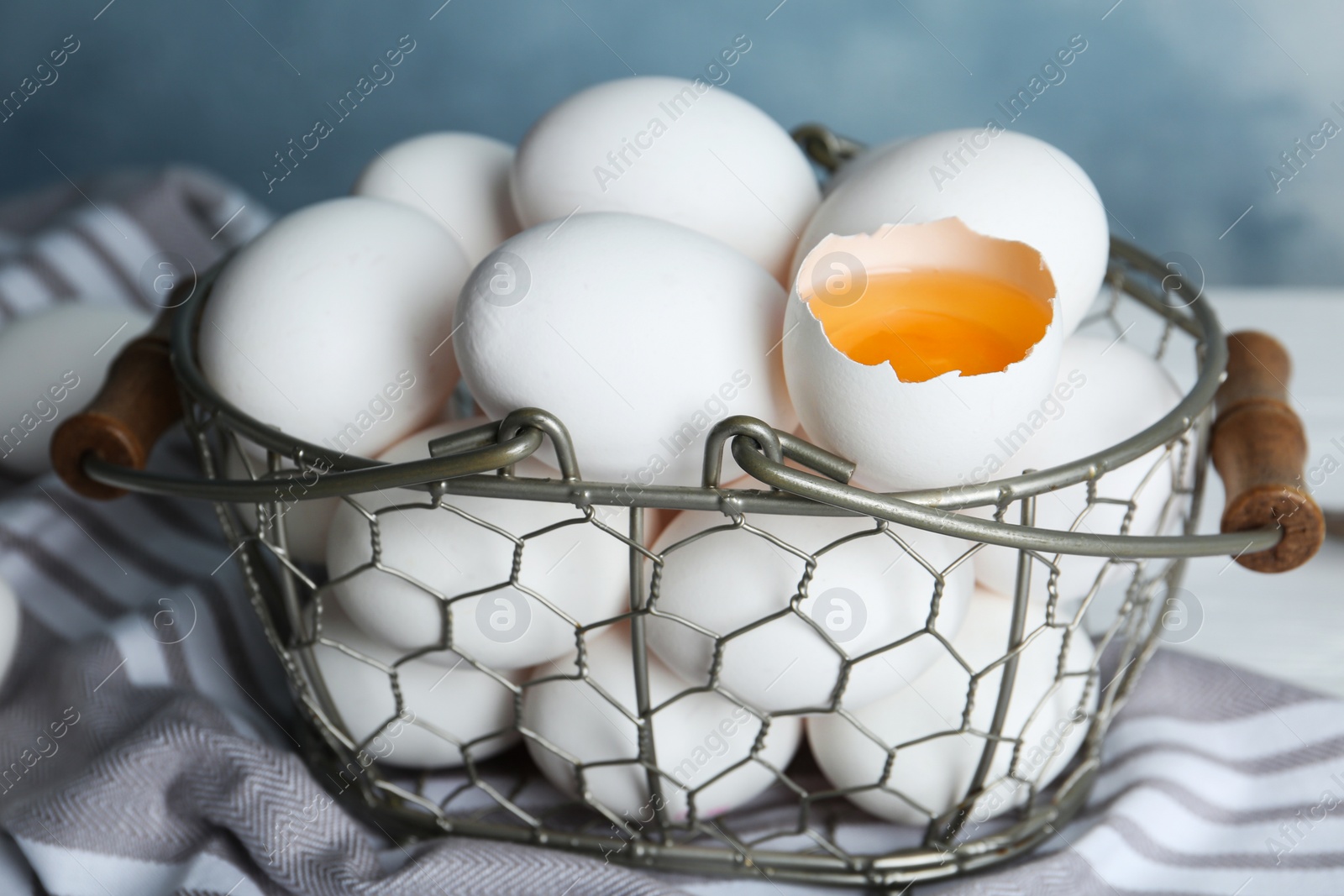 Photo of Chicken eggs in metal basket on table, closeup