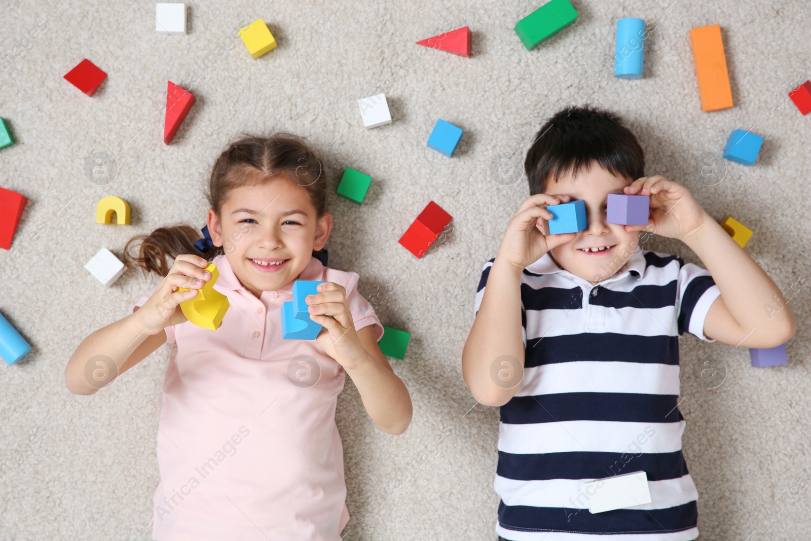 Photo of Cute children playing with colorful blocks on floor indoors, top view