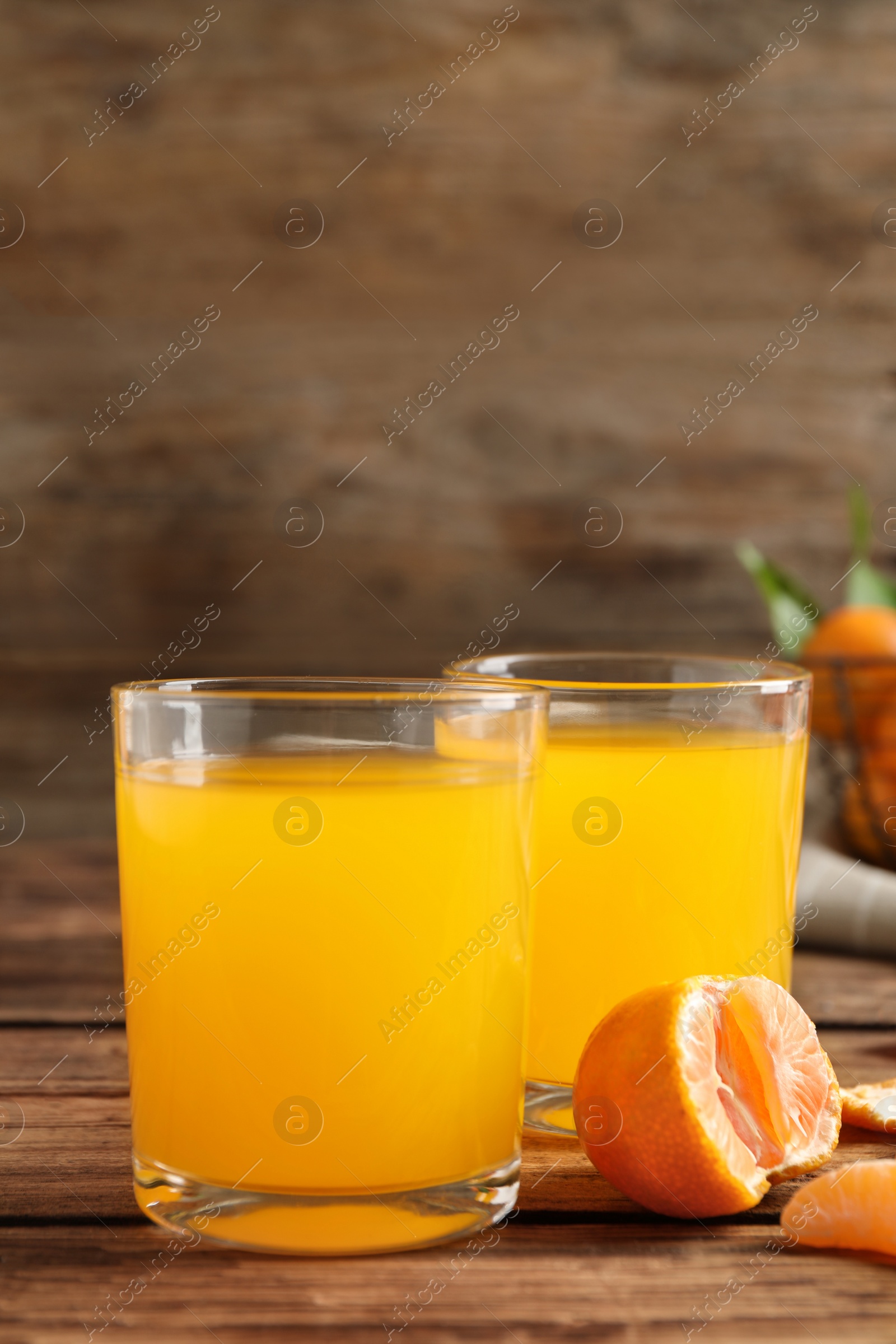 Photo of Glasses of fresh tangerine juice and fruits on wooden table