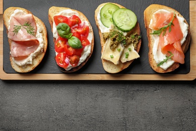 Board with different tasty bruschettas on grey table, flat lay. Space for text