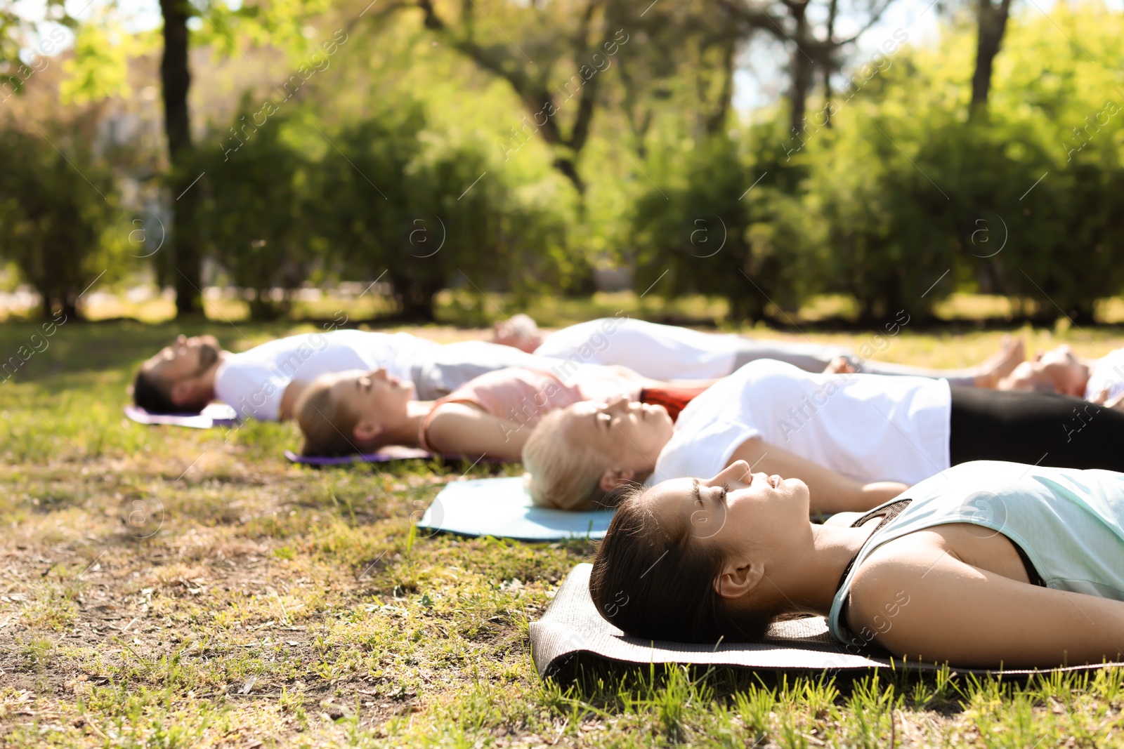 Photo of Group of people practicing yoga in park on sunny day