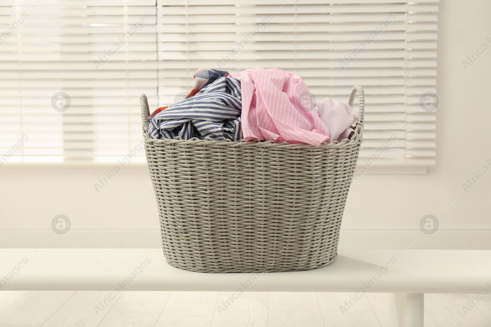 Photo of Wicker basket with dirty laundry in room