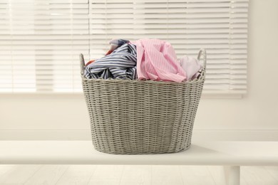 Photo of Wicker basket with dirty laundry in room