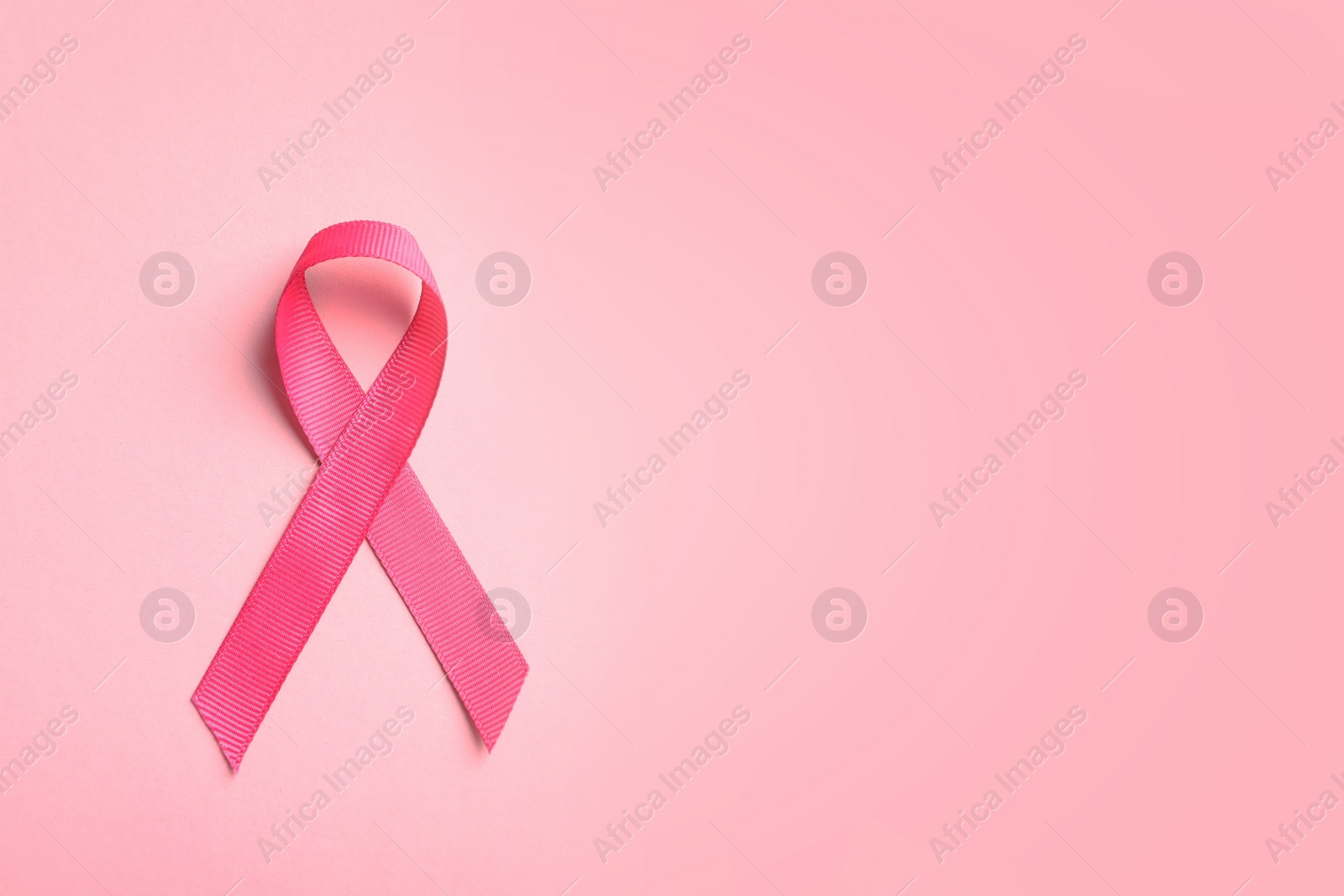 Photo of Pink ribbon on color background, top view. Cancer awareness