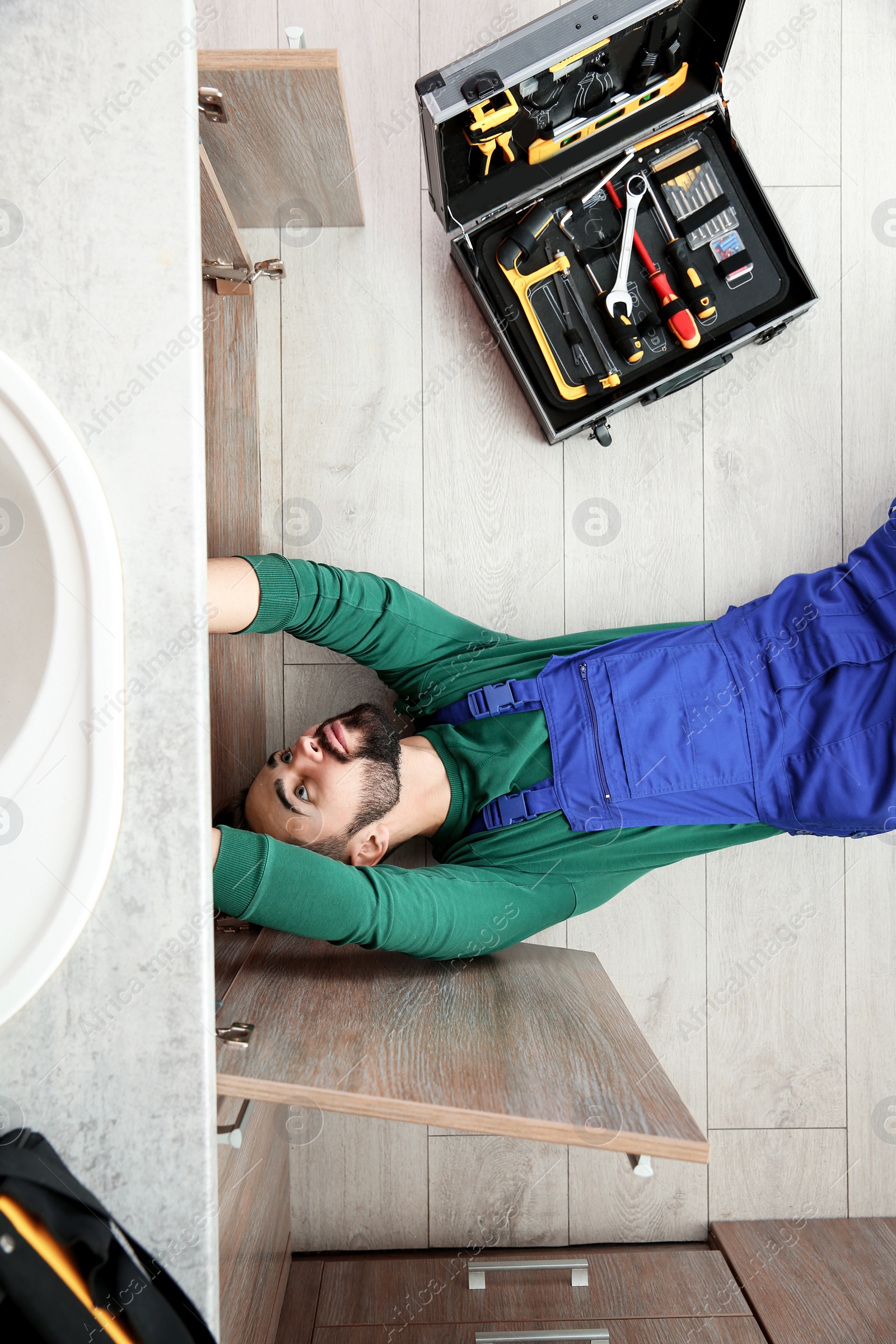 Photo of Male plumber repairing kitchen sink, top view