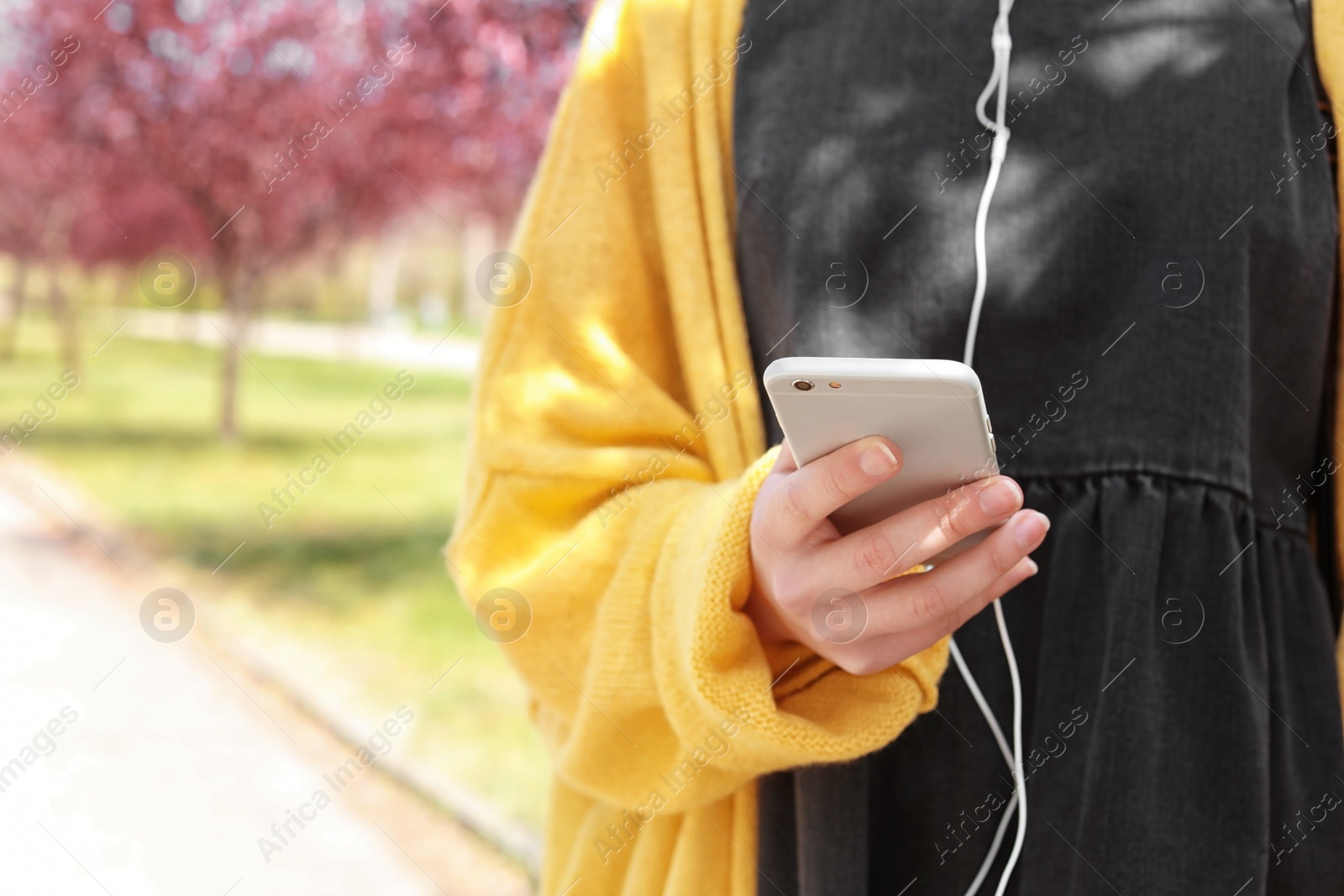 Photo of Young woman using phone for listening to music outdoors