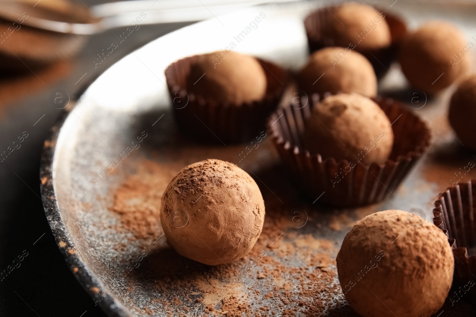 Photo of Plate with tasty chocolate truffles on grey table, closeup