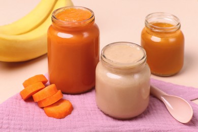 Healthy baby food, spoon and ingredients on pale pink background