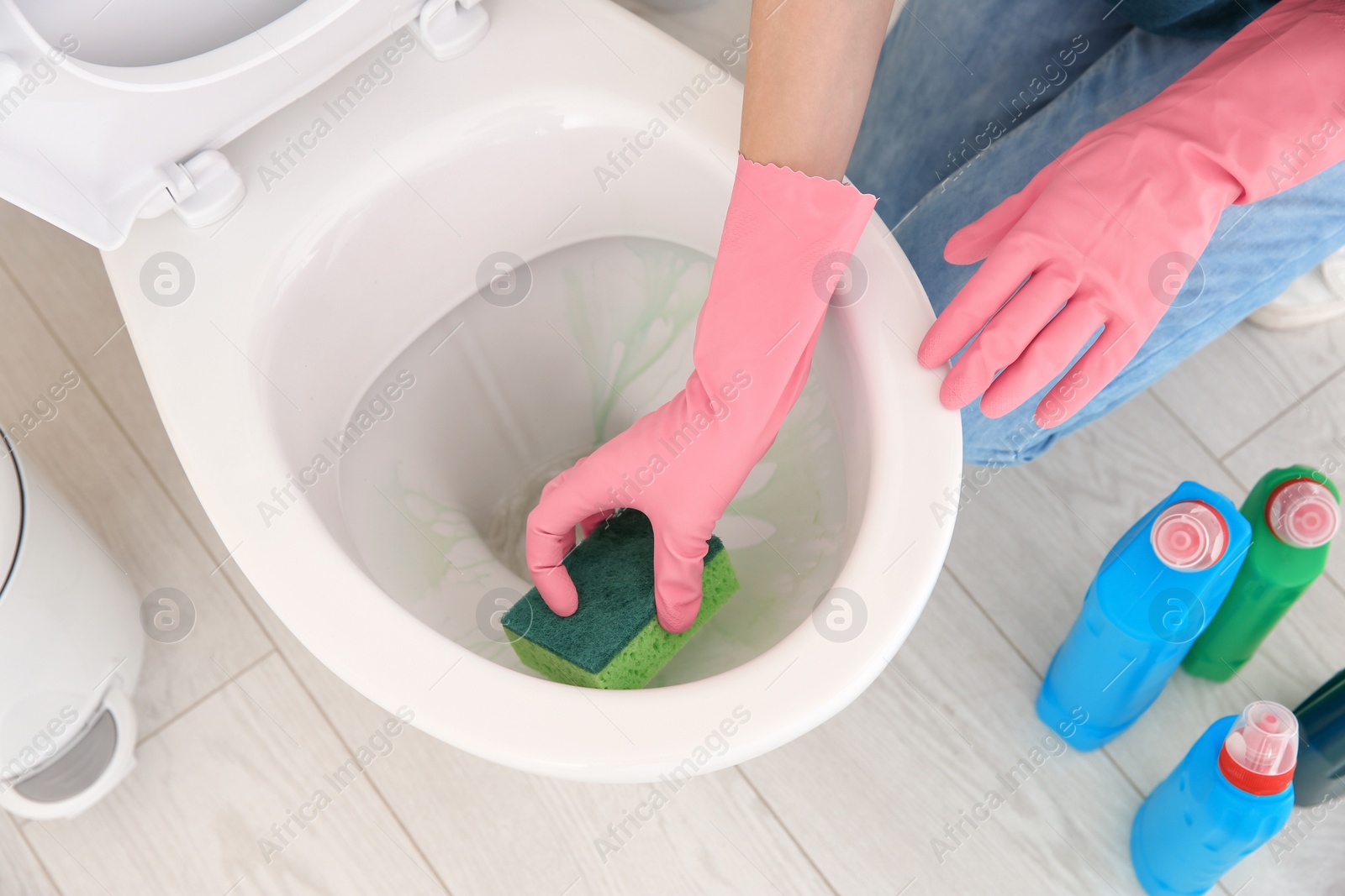 Photo of Woman cleaning toilet bowl in bathroom