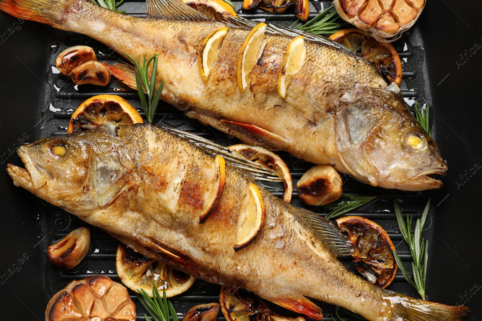 Photo of Tasty homemade roasted perches in grill pan, flat lay. River fish