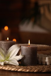 Photo of Spa composition with burning candles, lily flower and towels on wooden table in wellness center, space for text