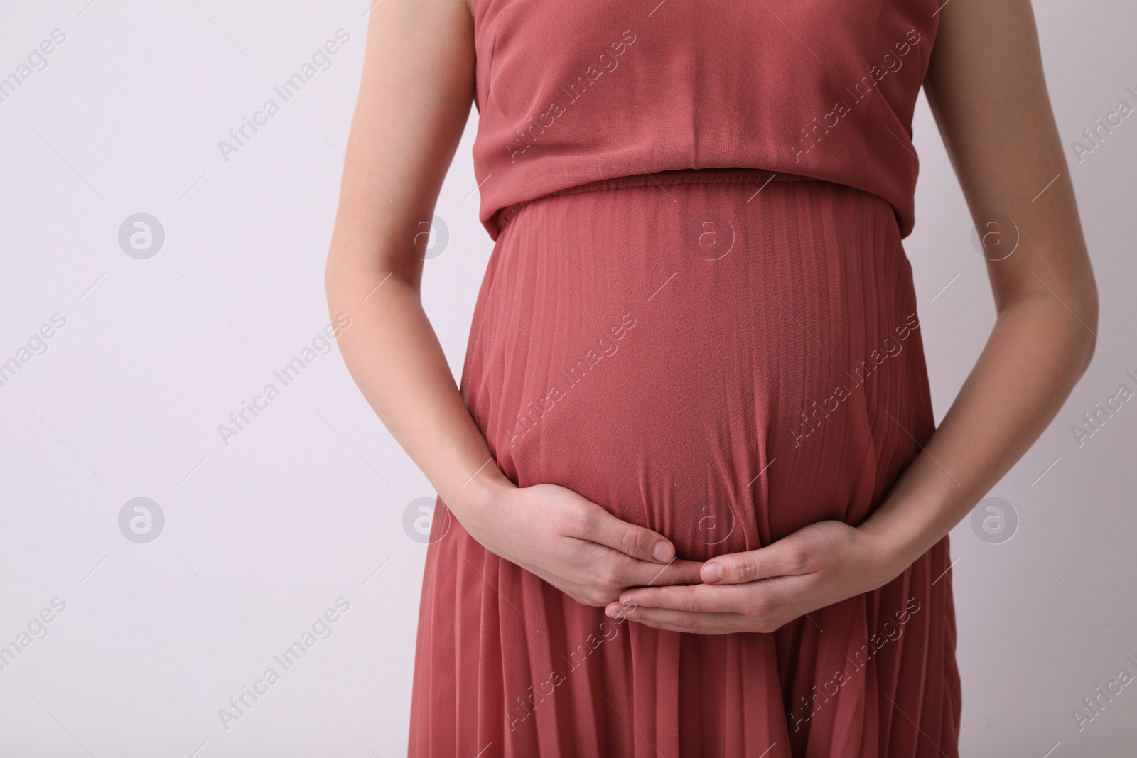 Photo of Young pregnant woman on light background, closeup. Space for text