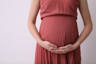 Young pregnant woman on light background, closeup. Space for text
