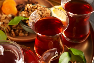 Photo of Tray with glasses of traditional Turkish tea, pot and ingredients, closeup