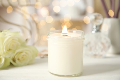 Photo of Burning candle in glass holder on white table