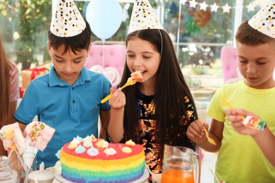 Happy children eating delicious cake at birthday party indoors