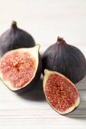 Whole and cut ripe figs on white wooden table, closeup