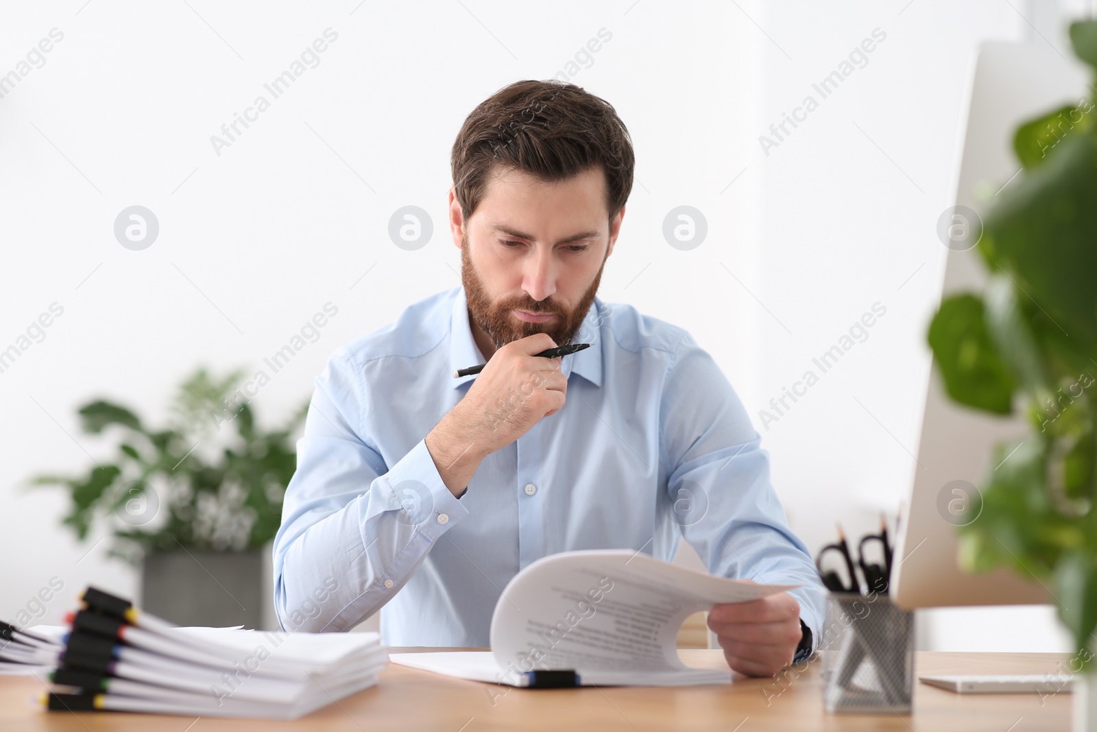 Photo of Businessman working with documents at wooden table in office