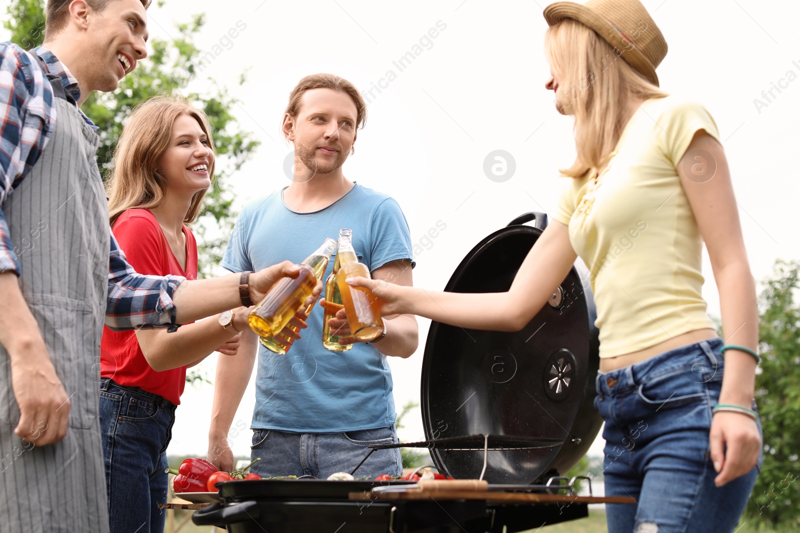 Photo of Young people having barbecue with modern grill outdoors