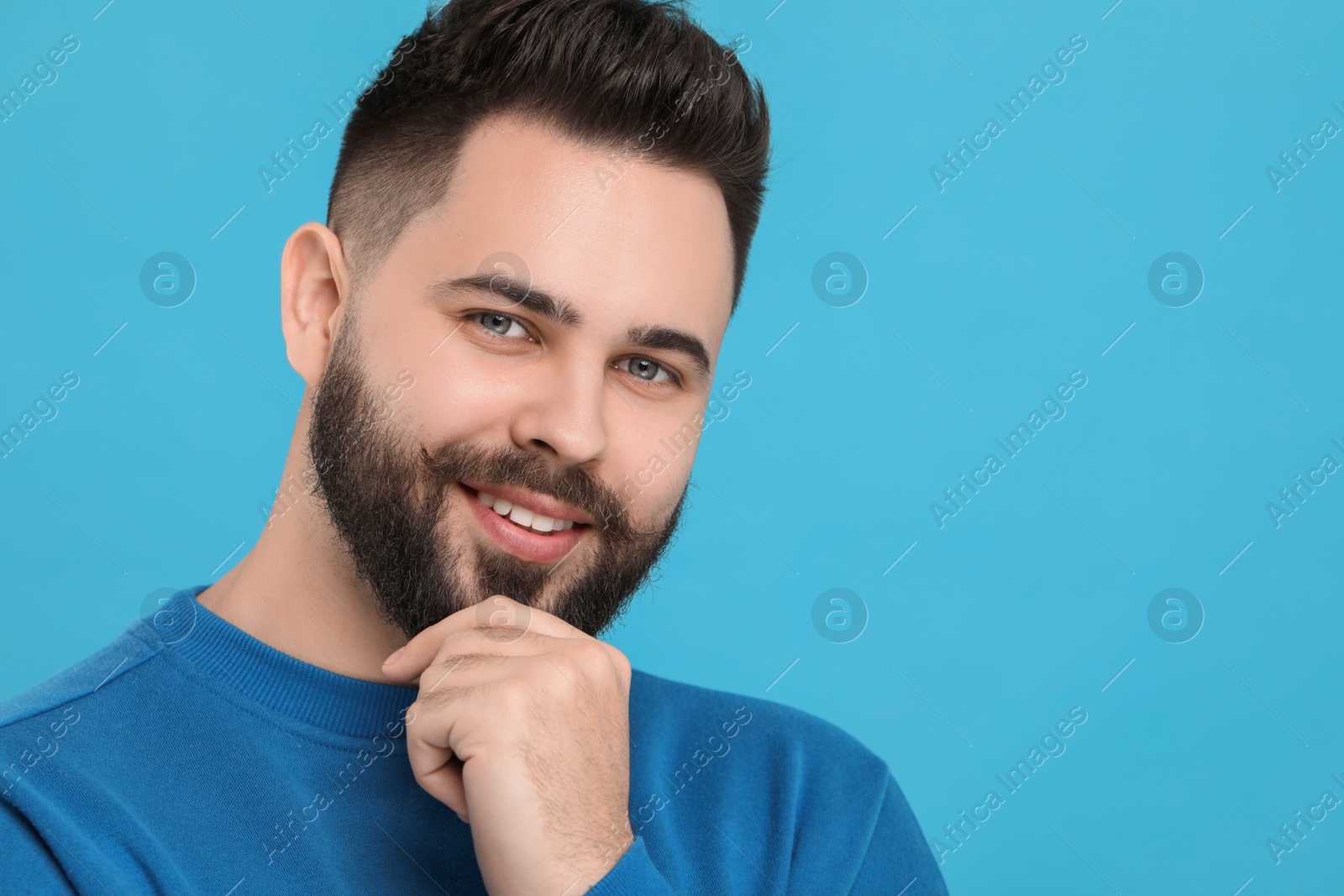 Photo of Portrait of happy young man with mustache on light blue background
