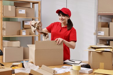 Photo of Post office worker packing parcel at wooden table indoors