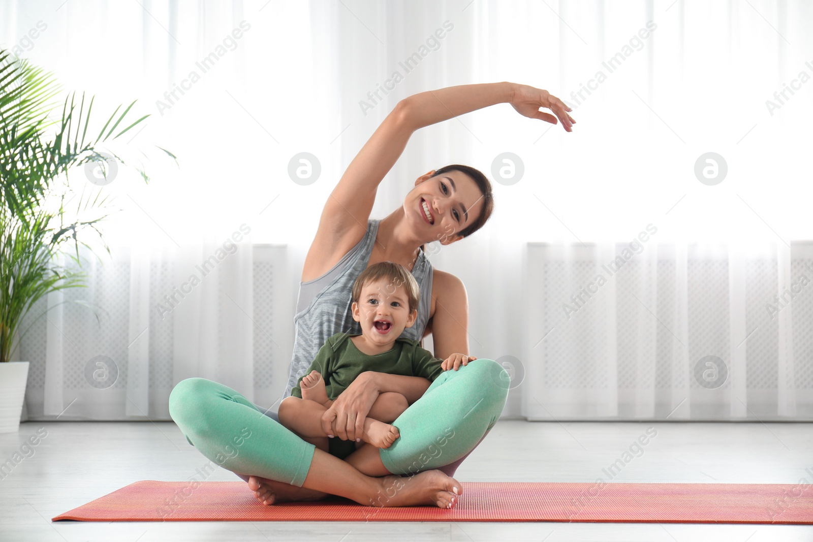 Photo of Young woman doing exercise with her son indoors. Home fitness