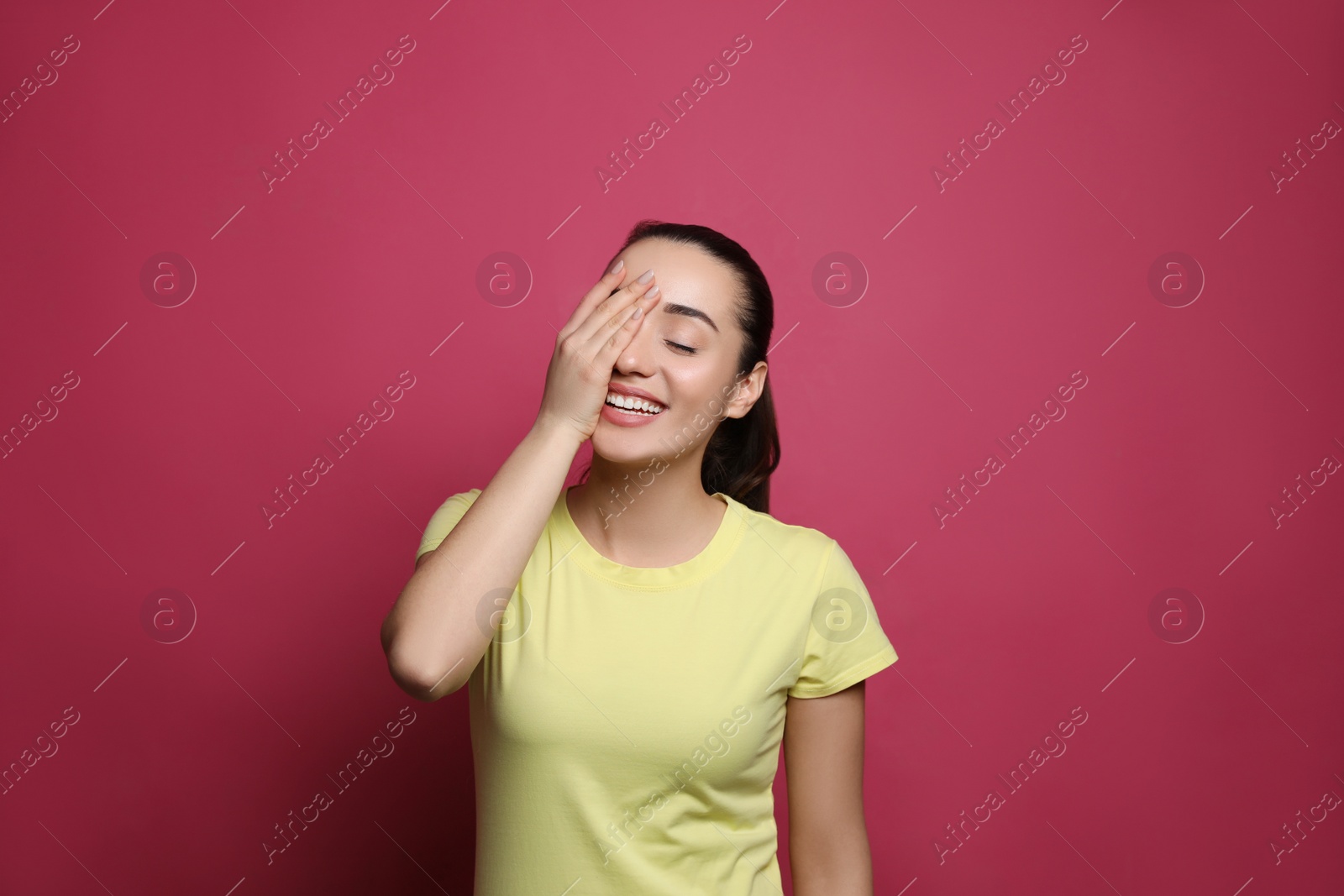 Photo of Beautiful young woman laughing on maroon background. Funny joke