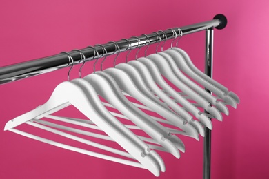 Metal rack with clothes hangers on color background