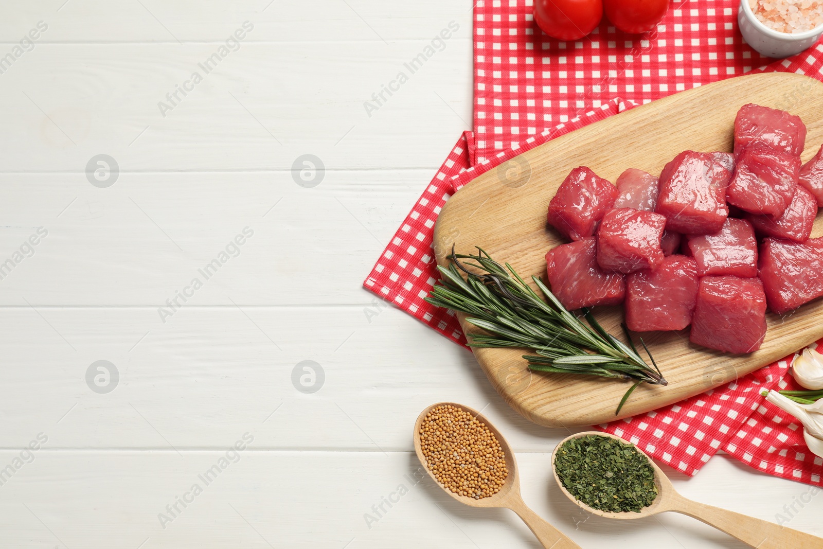 Photo of Raw beef meat and different ingredients for cooking delicious goulash on white wooden table, flat lay. Space for text