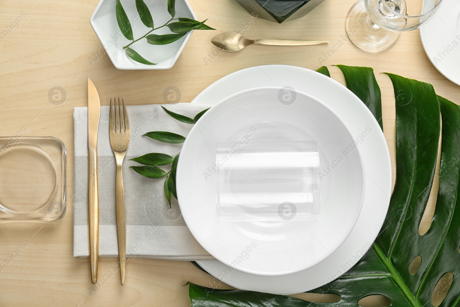 Photo of Elegant table setting with green tropical leaves, flat lay