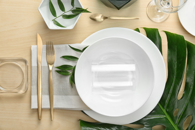 Photo of Elegant table setting with green tropical leaves, flat lay