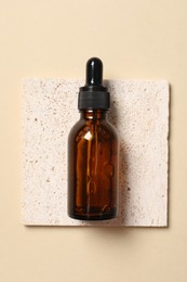 Photo of Bottle of cosmetic serum on beige background, top view