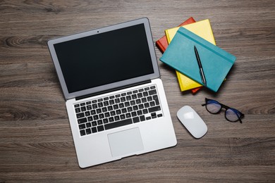 Photo of Modern laptop, glasses and office stationery on wooden table, flat lay. Distance learning