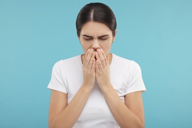 Photo of Woman coughing on light blue background. Cold symptoms
