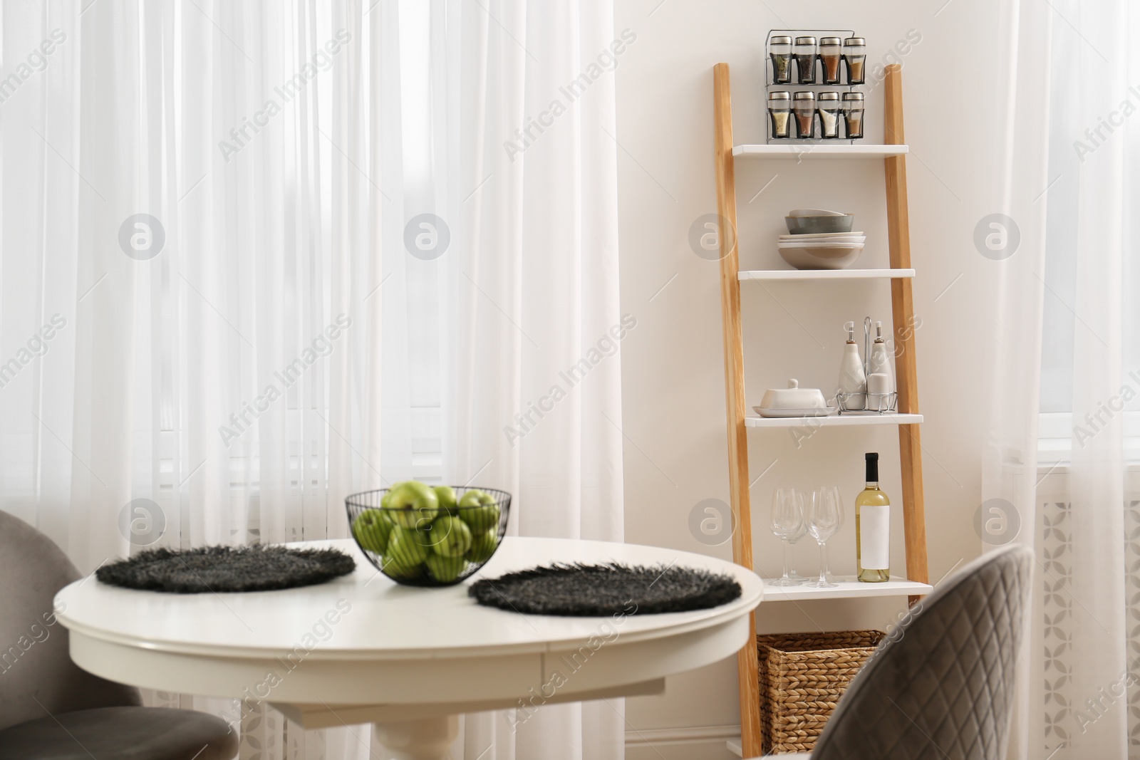 Photo of Stylish ladder shelf with kitchenware in dining room