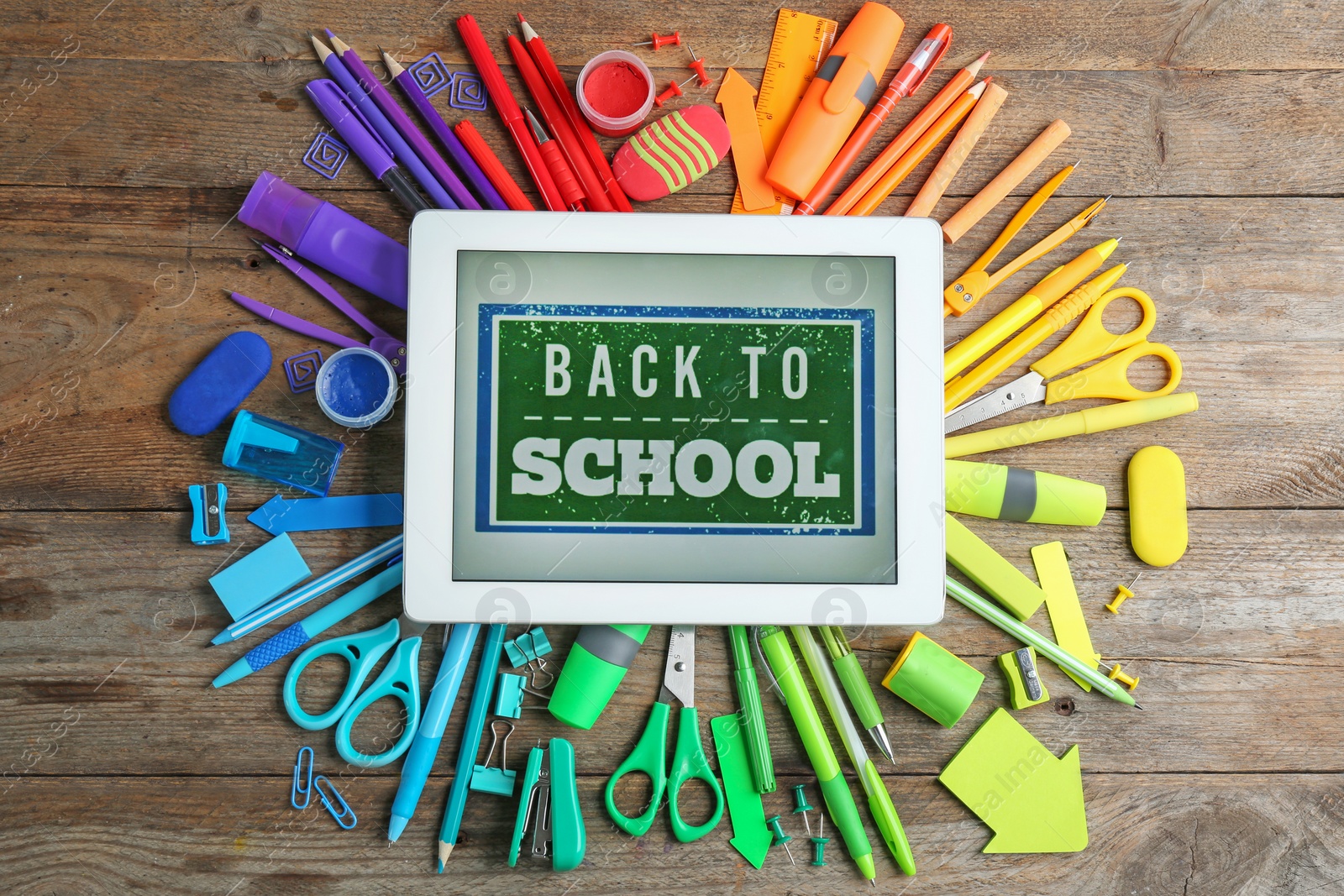 Photo of Tablet with phrase "BACK TO SCHOOL" and different stationery on wooden background, flat lay