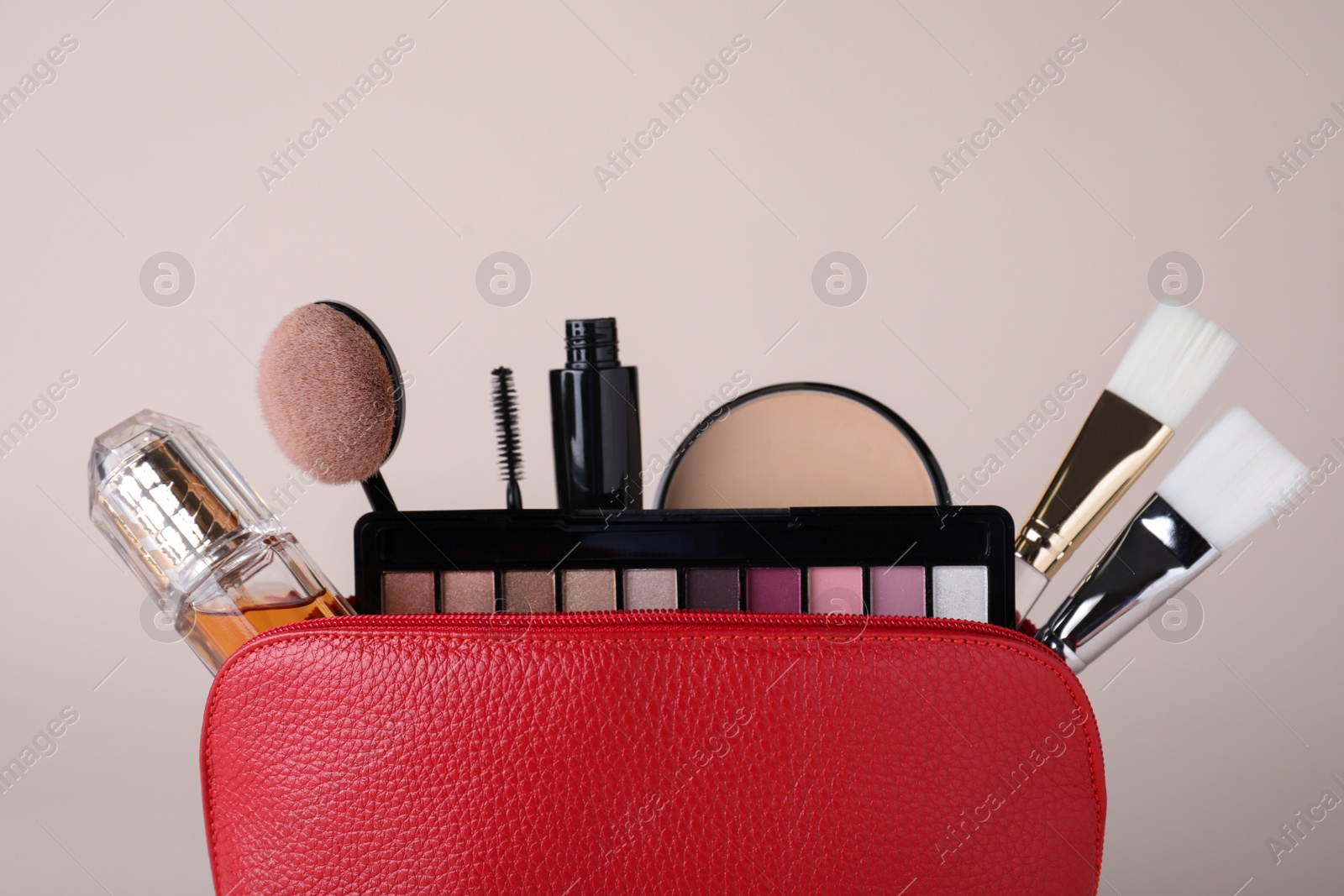 Photo of Cosmetic bag with makeup products and accessories on beige background. Space for text