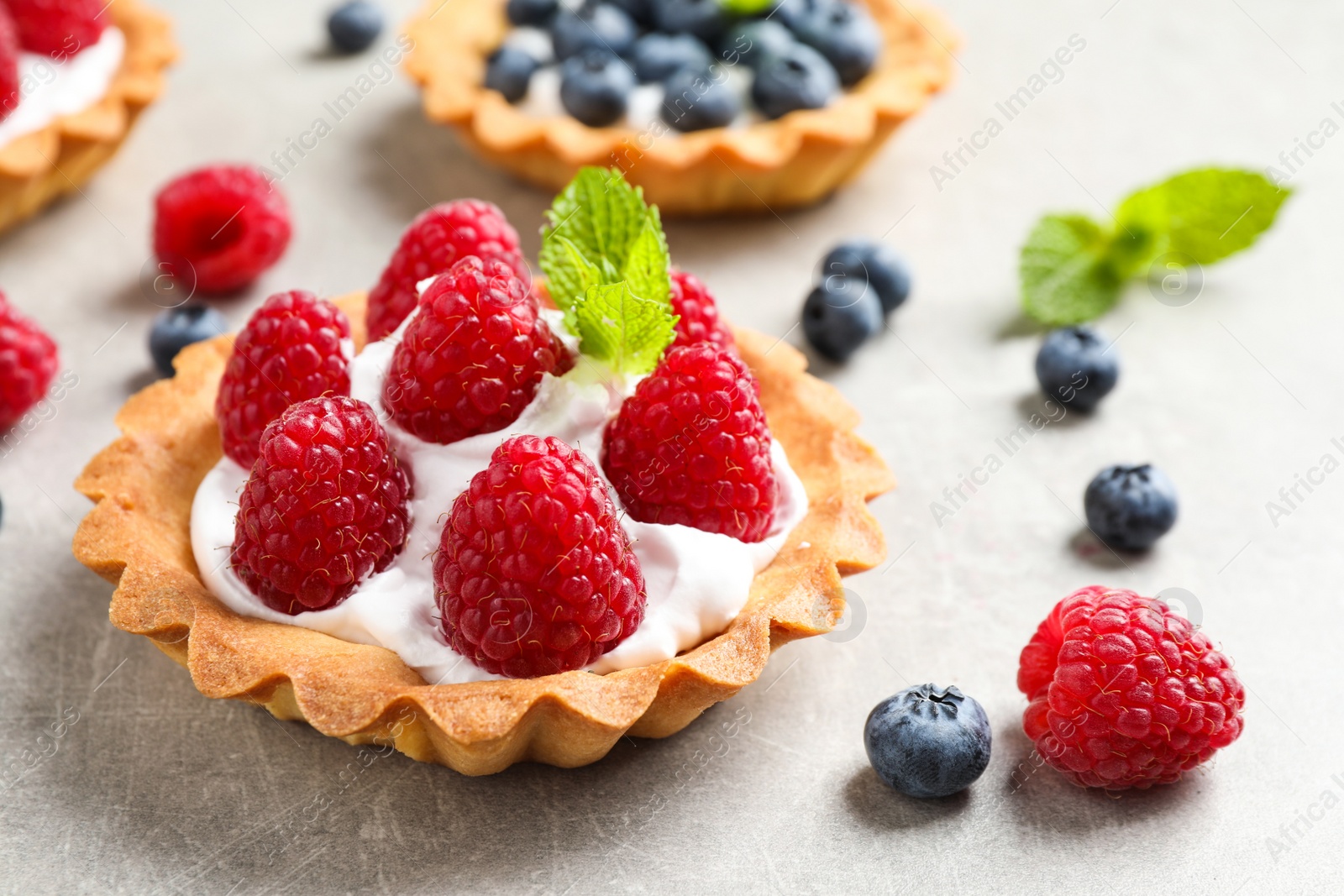 Photo of Delicious sweet pastry with berries on grey table