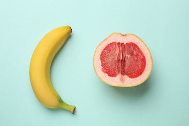 Photo of Banana and half of grapefruit on turquoise background, flat lay. Sex concept