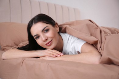 Photo of Woman lying in comfortable bed with beige linens