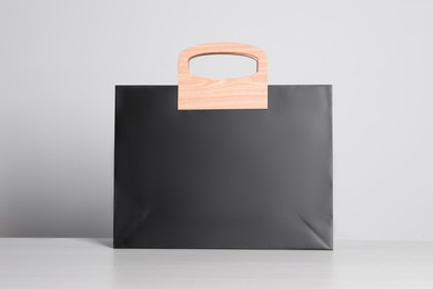 Black paper bag on white wooden table