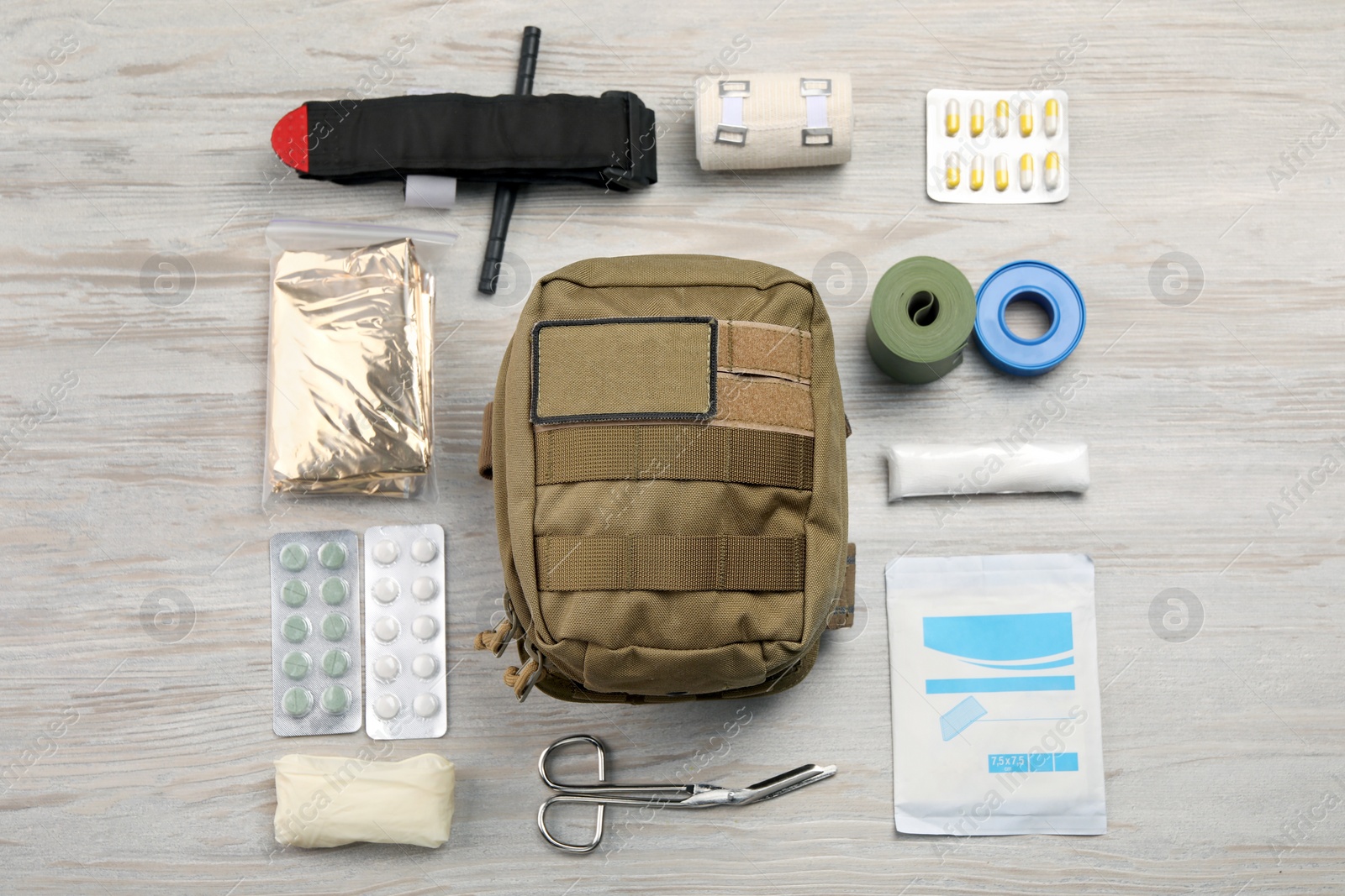 Photo of Military first aid kit on wooden table, flat lay