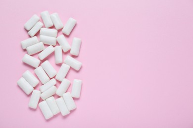 Photo of Tasty white chewing gums on pale pink background, flat lay. Space for text