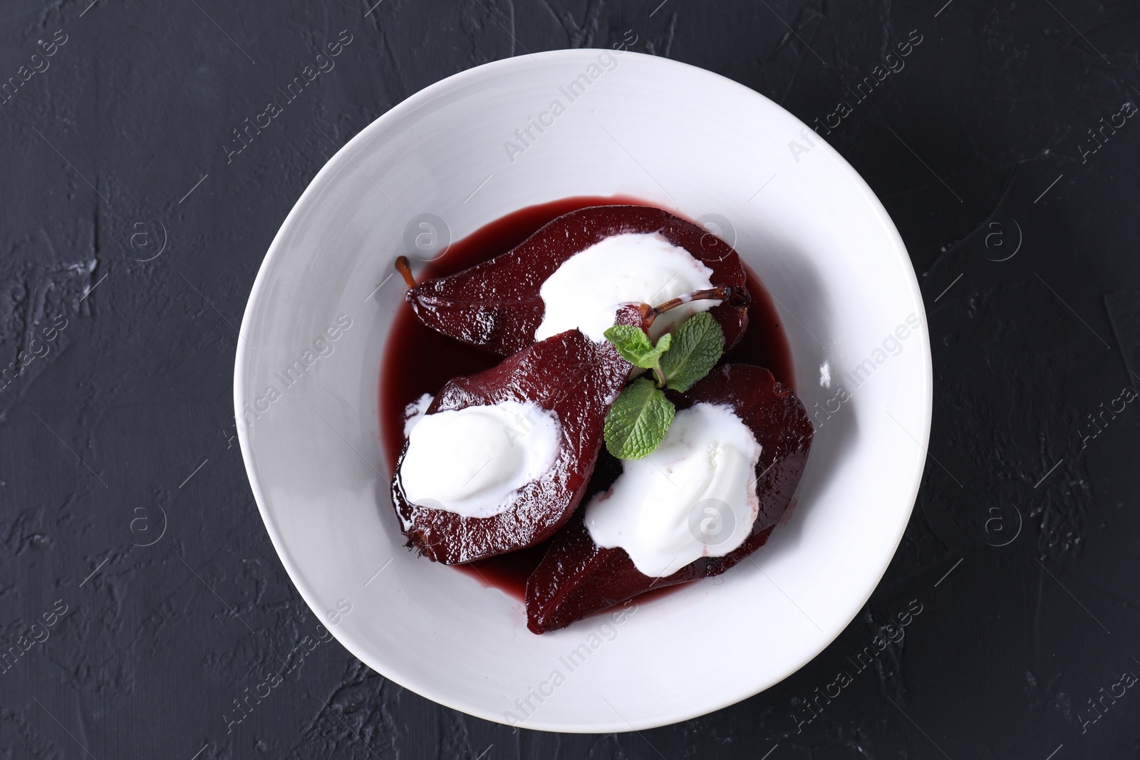 Photo of Tasty red wine poached pears and ice cream on black table, top view