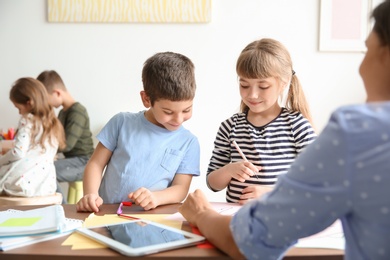 Cute little children with teacher in classroom at school