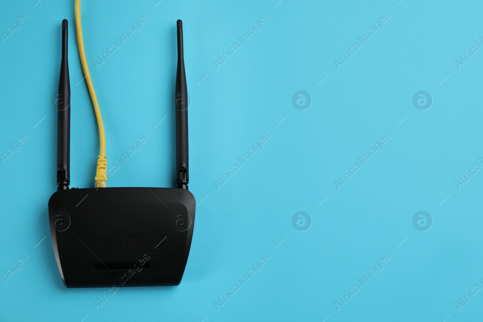 Photo of Modern Wi-Fi router on light blue background, top view. Space for text